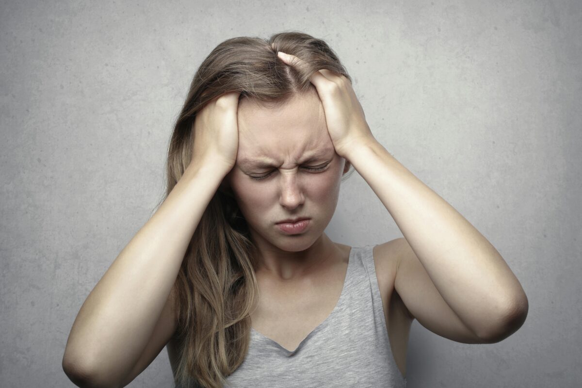 Young cat breeder expressing stress and frustration while holding her head.